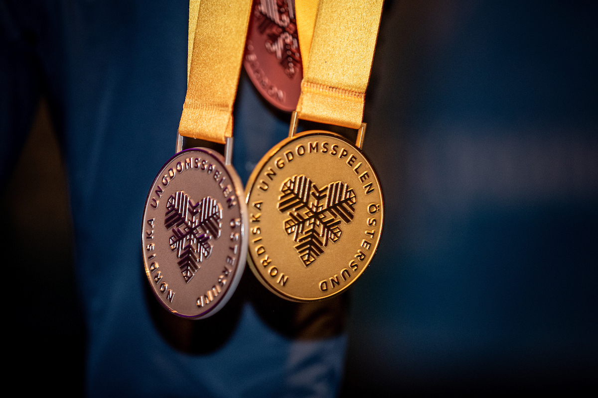 Medaljer från Nordiska Ungdomsspelen hänger över en blå jacka