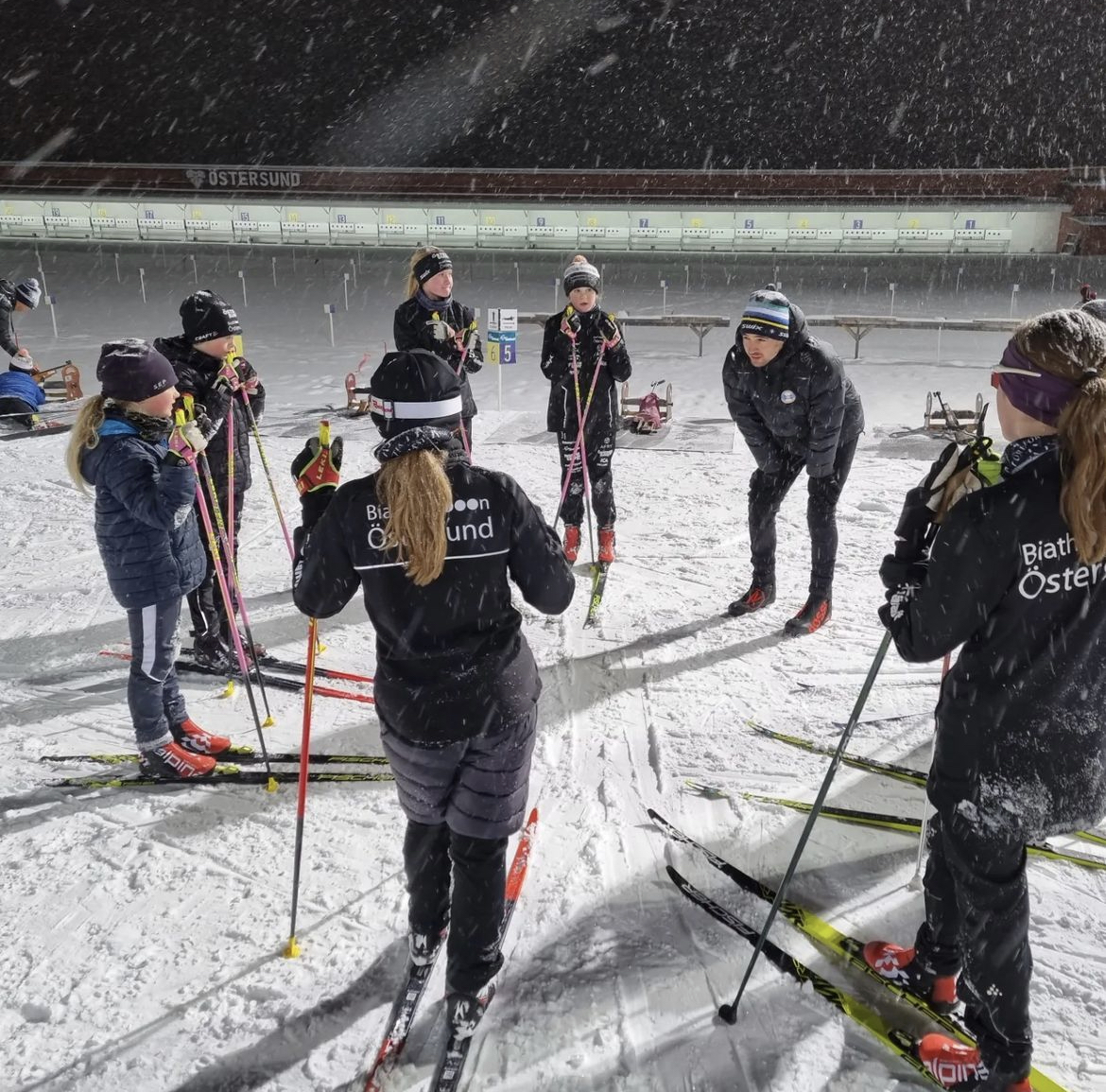Ett 10-tal barn med skidor lyssnar på genomgång inför träning